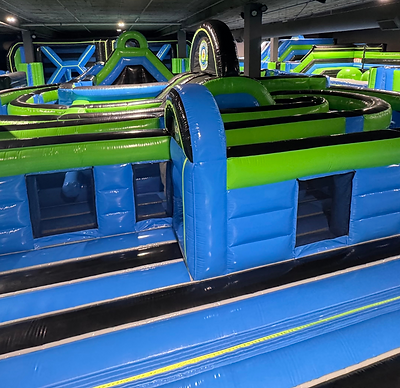 Bright blue and green inflatable obstacle course at Extreme Bounce, part of North America’s largest indoor inflatapark, featuring tunnels, climbing walls, and racing lanes.
