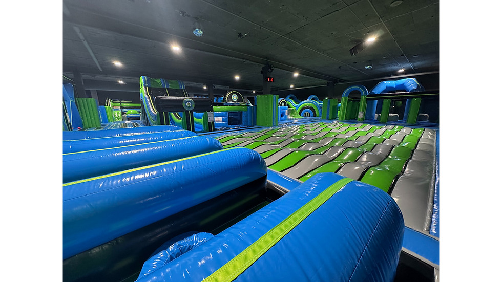 Wide-angle view showing multiple inflatable tracks and obstacle areas under ceiling lights.