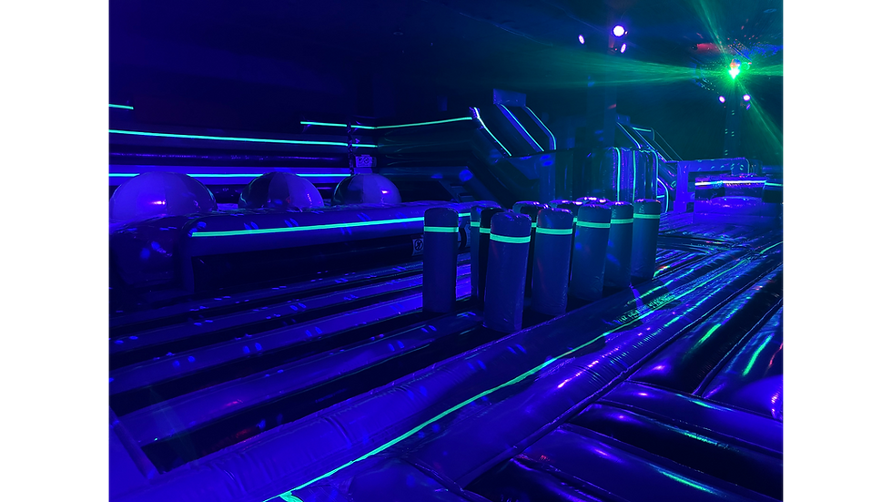 Colorful inflatable obstacle course with upright foam pillars glowing under blacklight lighting.